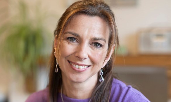 Headshot of a woman with long brown hair smiling to camera.